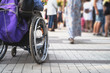 © DedMityay - Wheelchair with disabled man on blurred background of many people on street. Problem of people with disabilities and society concept