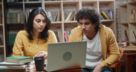 Wall Mural - Two cheerful asian students working on a project together, using books and laptop, brainstorming and preparing for exams - collaboration, student lifestyle concept 4k