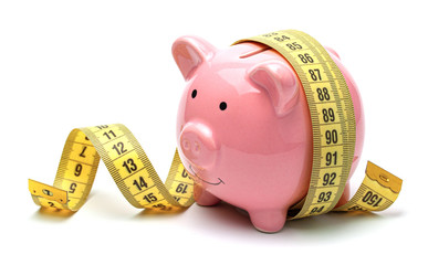 Pink piggy bank and yellow measuring tape isolated on a white background