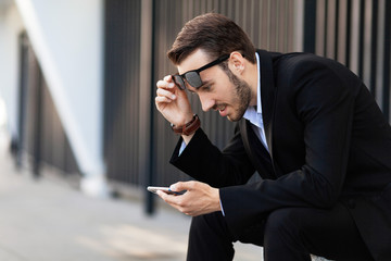 Young man in suit looks in surprise on phone.