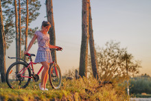 Young Girl With A Bicycle At The Edge Of The Autumn Pine Forest