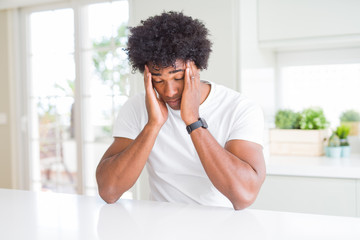 Poster - Young african american man wearing casual white t-shirt sitting at home with hand on headache because stress. Suffering migraine.