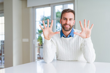 Wall Mural - Handsome man wearing casual sweater showing and pointing up with fingers number ten while smiling confident and happy.