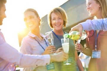 Wall Mural - Businessman pouring wine from bottle to colleagues during success party