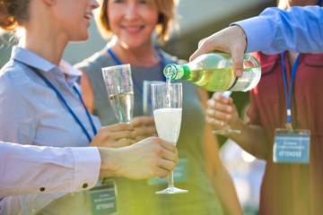 Poster - Businessman pouring wine from bottle to colleagues during success party