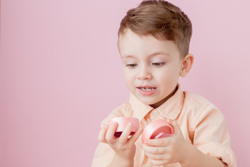 Wall Mural - Happy little boy with a gift . Photo isolated on pink background. Smiling boy holds present box. Concept of holidays and birthday