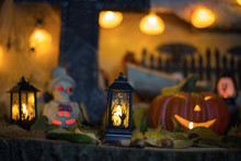 Halloween Decorations Concept At Night. Close Up Of Jack O'lantern, Vintage Lanterns, Pumpkins, Skull, Autumn Leaves. Colorful Halloween Lights On Evening. Happy Halloween Scene On Wooden Background