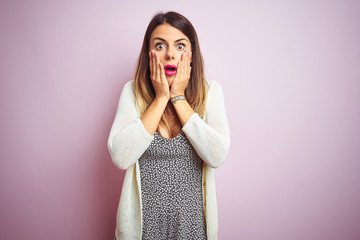 Poster - Young beautiful woman standing over pink isolated background afraid and shocked, surprise and amazed expression with hands on face