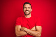 © Krakenimages.com - Young handsome man wearing casual t-shirt over red isolated background happy face smiling with crossed arms looking at the camera. Positive person.