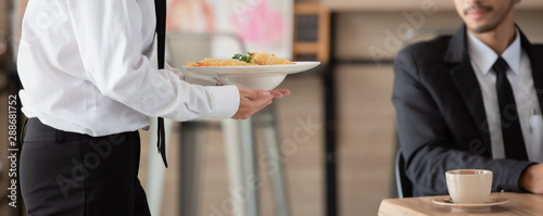 Cuadros en Lienzo Waiter with plate of food in hand serving at table at restaurant, health care concept