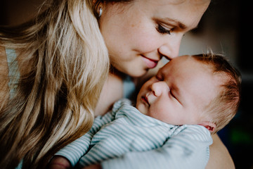 A beautiful young mother with a newborn baby at home.