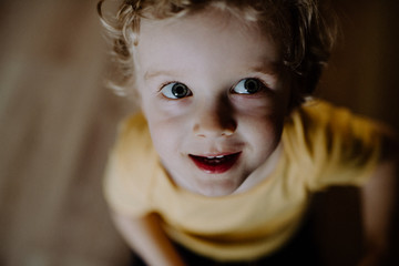 Wall Mural - A top view of a toddler boy at home, looking up.