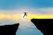 canvas print picture - Man jump through the gap between hill.man jumping over cliff