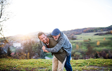 Wall Mural - Senior father and his son walking in nature, having fun.