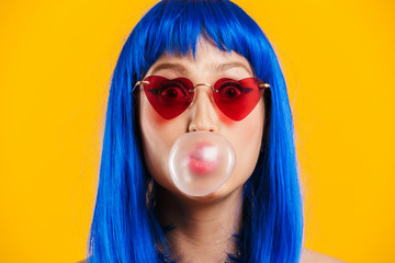 Canvas Print - Portrait of young caucasian woman wearing blue wig and sunglasses looking at camera and blowing bubble gum