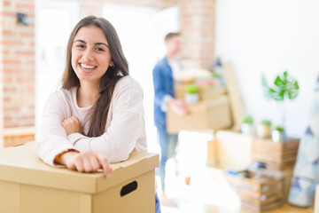 Poster - Beautiful young couple moving to a new home, young woman smiling happy to the camera excited for new apartment