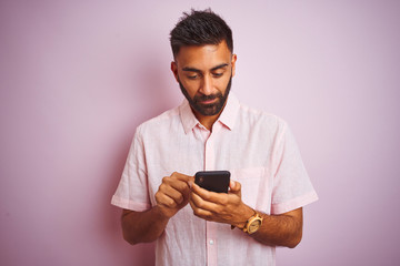 Poster - Young indian man using smartphone standing over isolated pink background with a confident expression on smart face thinking serious