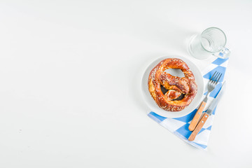 Wall Mural - Oktoberfest festive cutlery set  with with a traditional checkered  tablecloth, plate, pretzel, fork, knife and a glass of beer. background for Restoration menu