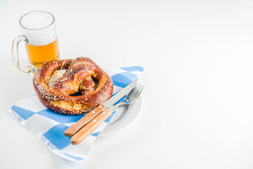 Wall Mural - Oktoberfest festive cutlery set  with with a traditional checkered  tablecloth, plate, pretzel, fork, knife and a glass of beer. background for Restoration menu