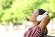 © Antonioguillem - Happy mixed race woman listening to music resting in a park