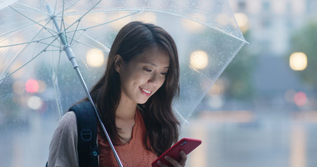 Wall Mural - Woman use of mobile phone and hold with umbrella in the evening