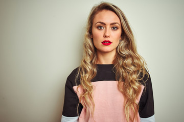 Poster - Young attractive woman wearing sweatshirt standing over white isolated background with serious expression on face. Simple and natural looking at the camera.