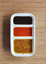 Chicken Rice Side Dish Sauce,Asian Dips Style In Black Soybean,red Chili And Yellow Ginger Sauce Put In Three Holes Sauce Sqaure Bowl Place On A Wooden Table Background.