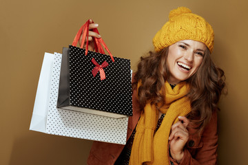 Wall Mural - smiling modern woman showing shopping bags on bronze background