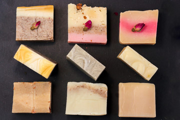 Fototapete - handmade multicolored soap with herbs and rosebuds on a black background with a blank space for text. Spa soap for face and body treatments flat lay istagram  style