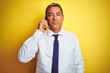 © Krakenimages.com - Middle age businessman talking on the smartphone over isolated yellow background with a confident expression on smart face thinking serious