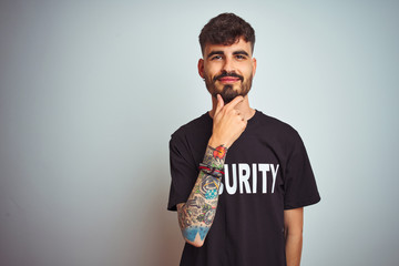 Sticker - Young safeguard man with tattoo wering security uniform over isolated white background looking confident at the camera with smile with crossed arms and hand raised on chin. Thinking positive.