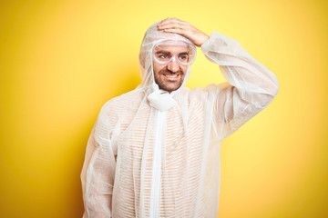 Sticker - Young man wearing painter equipment and safety glasses over isolated yellow background stressed with hand on head, shocked with shame and surprise face, angry and frustrated. Fear and upset