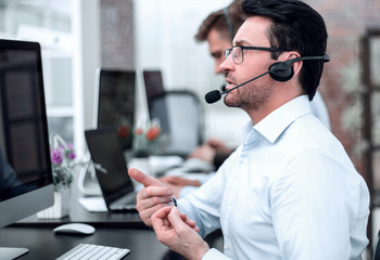 Wall Mural - attentive businessman in headphones sitting at the table call center.