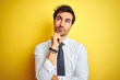 © Krakenimages.com - Young handsome businessman wearing elegant shirt and tie over isolated yellow background with hand on chin thinking about question, pensive expression. Smiling with thoughtful face. Doubt concept.