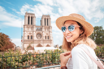 happy asian woman visiting famous notre dame cathedral after the fire. europe travel and sightseeing