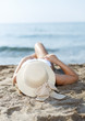 Closeup of girl in swimsuit and hat taking sunbath at sandy beach