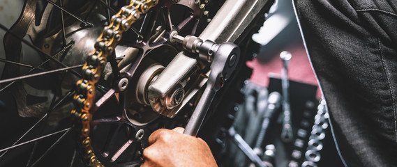 Mechanic working on motorcycle in garage. Repair service.