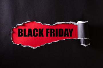 Wall Mural - Top view of Black torn paper and the text black friday on a red background. Black Friday composition.