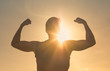 © kieferpix - Strong fit man flexing against sunset sky. People power and winning concept.