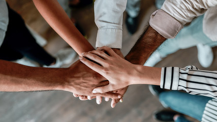 Cooperation. Top view of people holding hands together while standing in the office