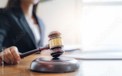Fotomural Woman judge hand holding gavel to bang on sounding block in the court room