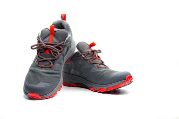 Men trekking shoes isolated on white background. Gray-red hiking shoes. Safety footwear for climbing. Adventure gear. Lightweight rubber trekking shoes with safety sole. Modern and breathable design.