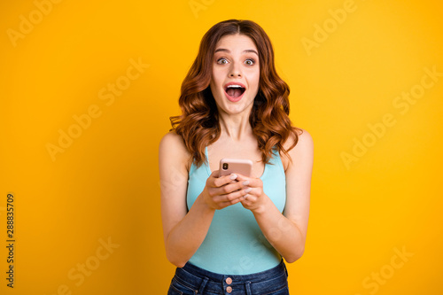 Photo of excited lady with open mouth holding telephone in hands wear blue tank-top isolated yellow background