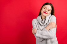 Pretty Overjoyed Lady With Closed Eyes Touching Soft Knitted Jumper Isolated On Red Background