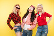 © Вячеслав Косько - Studio shot of trendy girls with head bows, sunglasses wearing trendy hipster clothes and smiling at camera. Isolate on yellow background.