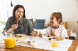 Image of beautiful family mother and little daughter eating together while having breakfast at home in morning