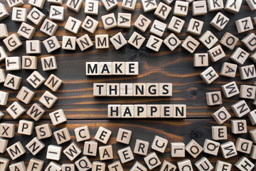 Wall Mural - make things happen - phrase from wooden blocks with letters, keep it simple motivational concept, random letters around, white  background