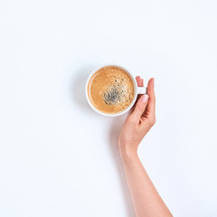 Wall Mural - White coffee cup in female hands on a white background. Top view