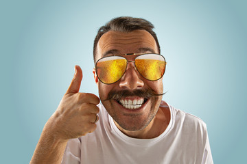 Wall Mural - Oktoberfest man with sunglasses full of light beer, looking at sea or ocean of alcohol on blue background. Facial expression, astonished, crazy happy.The celebration, holidays, festival concept. Enjoy