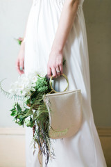 Wall Mural - Bride holding wedding bouquet and shimmery purse by side, woman holding evening clutch